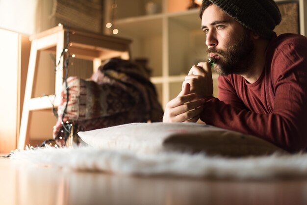 Young man with a knit cap using a vaper