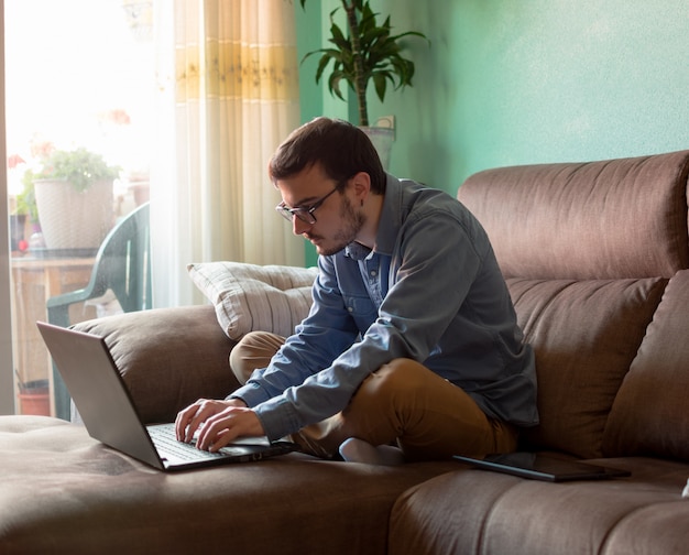 Young man with laptop on sofa at home