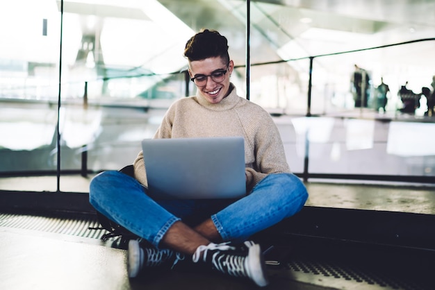 Young man with legs crossed working on tablet while sitting on floor