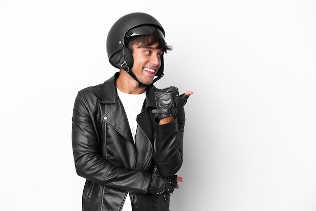 Young man with a motorcycle helmet isolated on white background pointing to the side to present a product