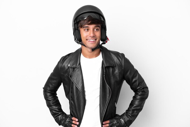 Young man with a motorcycle helmet isolated on white background posing with arms at hip and smiling