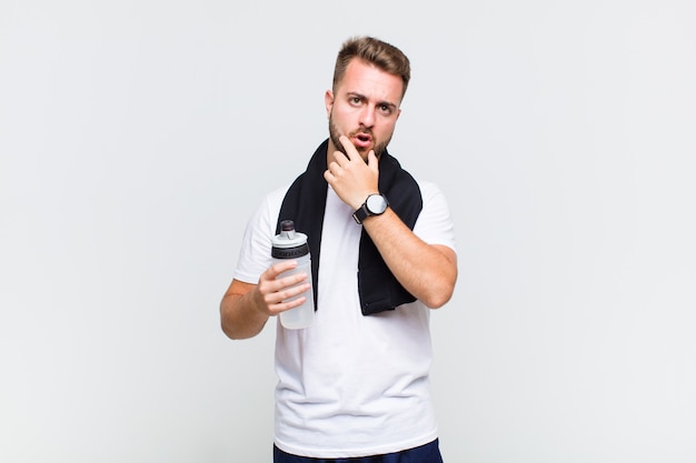 Young man with mouth and eyes wide open and hand on chin