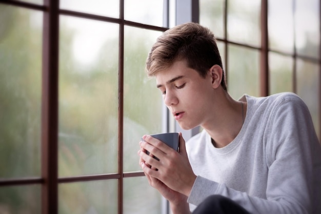 Young man with a mug near the window