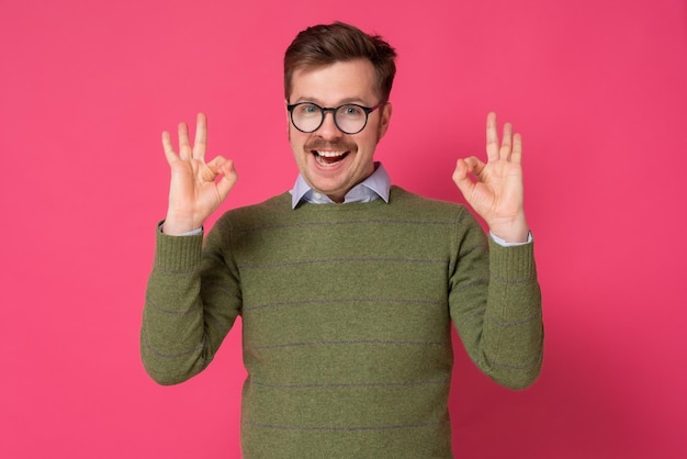 Photo young man with mustache gesturing ok sign on pink background