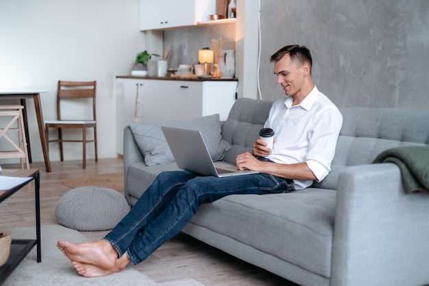 Young man with a takeaway coffee reading his email .