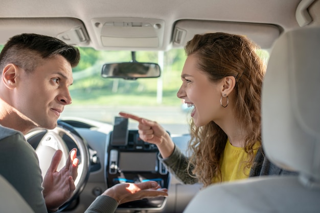 Young man and woman conflicting in a car salon