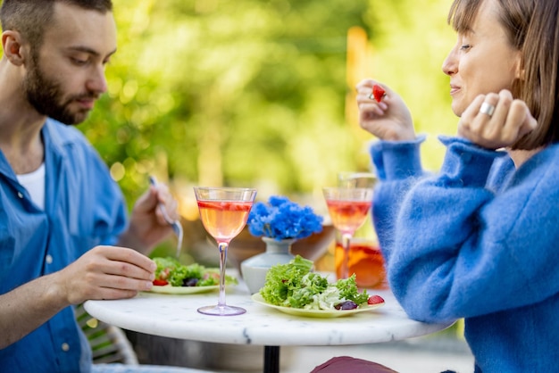 Young man and woman eating healthy food spending summer time together outdoors