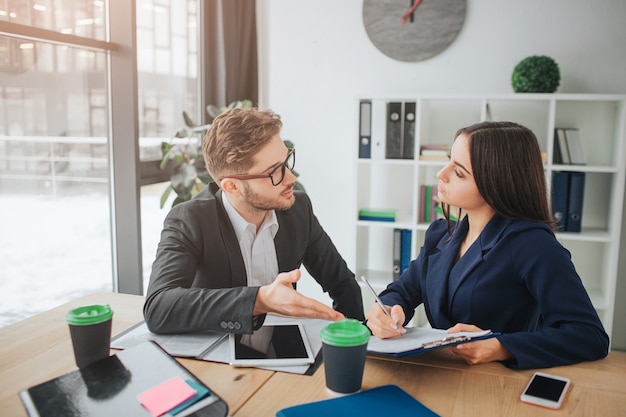 Young man and woman have conversation in meeting room at table