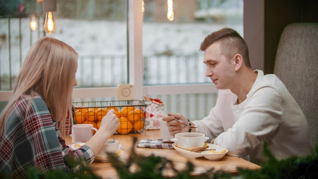 A young man and woman having a breakfast in cafe christmas time