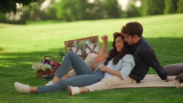 Young man and woman laughing outdoors Girl and guy sitting on blanket in park