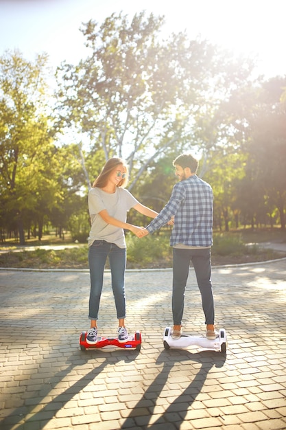 Young man and woman riding on the Hoverboard in the park content technologies a new movement