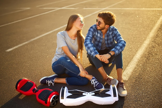 Young man and woman riding on the Hoverboard in the park content technologies a new movement