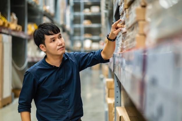 Young man worker checking inventory in the warehouse store