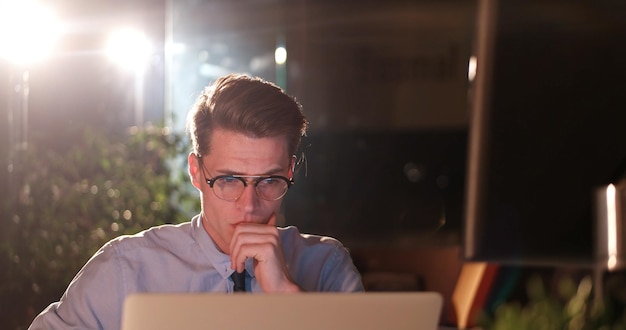 Young man working on computer at night in dark office. The designer works in the later time.