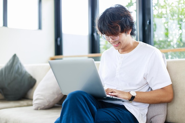 Young man working from home office sit on sofa in living room Happy Asian businessman concept