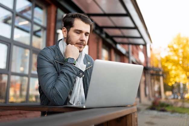 Young man working on a laptop outside