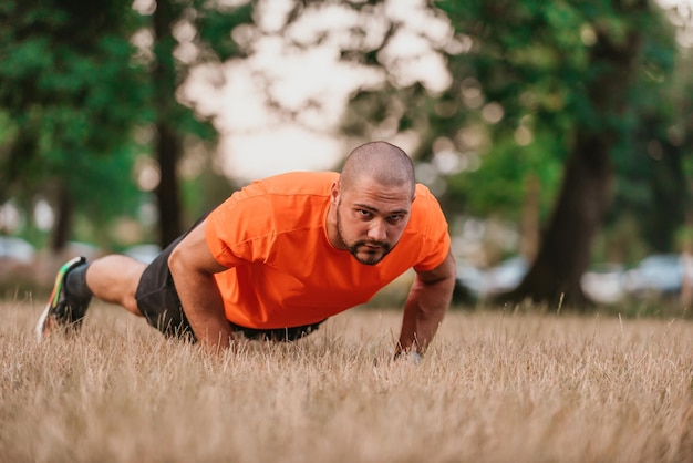 Young man working out doing pushups in park as he warms up for his daily workout or jog