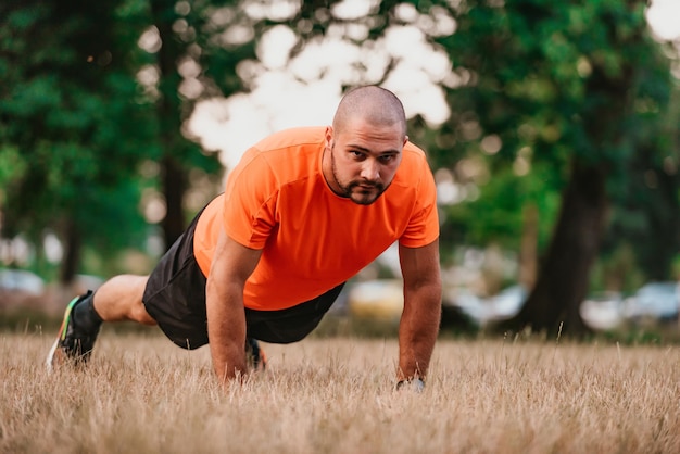 Young man working out doing pushups in park as he warms up for his daily workout or jog