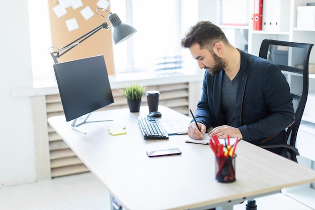 The young man works in the office at a computer Desk with documents