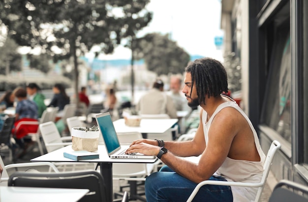 young man works with computer in an outdoor cafe