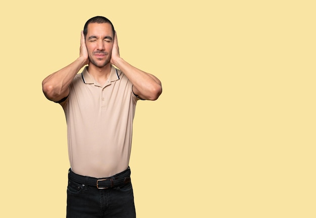 Young man worried about loud noises and covering his ears