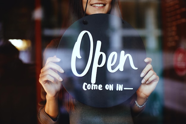 Young manager girl changing a sign from closed to open sign on door cafe