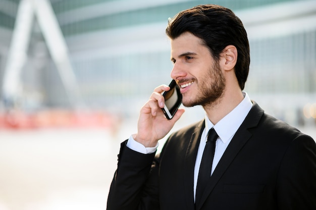 Young manager on the phone outdoor in an urban setting