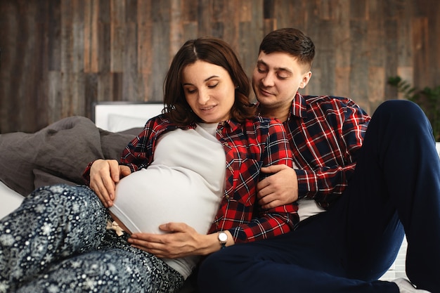 young married couple awaiting a baby. Beautiful couple lying in the bedroom make plans for the birth of a baby. First child, postpartum, young family.