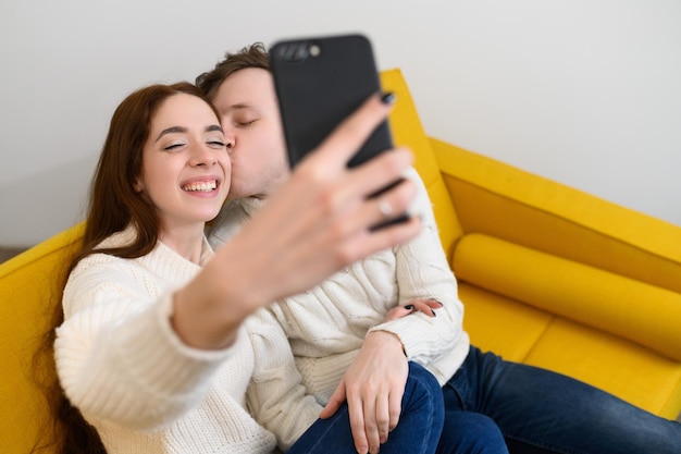 A young married couple at home they sit on the couch and take selfies