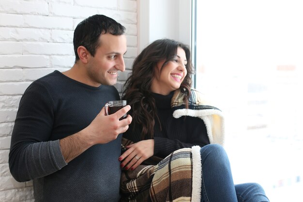 A young married couple looks out the window of a new apartment