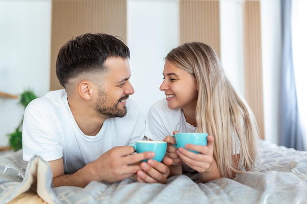 Young married couple in love having coffee in their bed Good morning Healthy breakfast in bed Young beautiful love couple is having coffee in bed