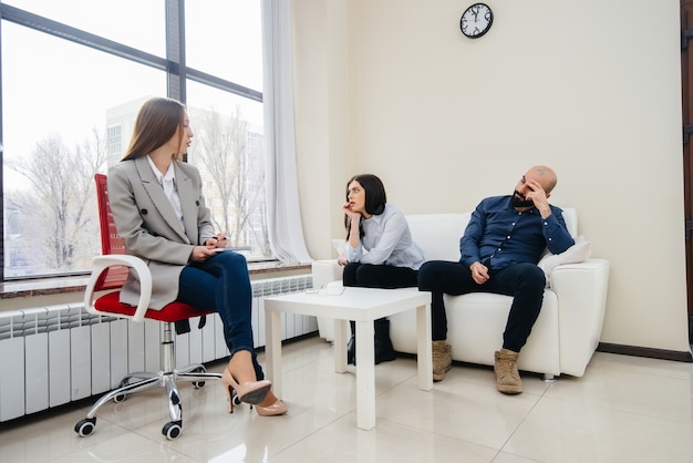 A young married couple of men and women talk to a psychologist at a therapy session. Psychology.