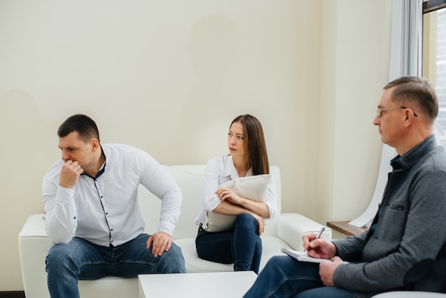 A young married couple of men and women talk to a psychologist at a therapy session. Psychology.