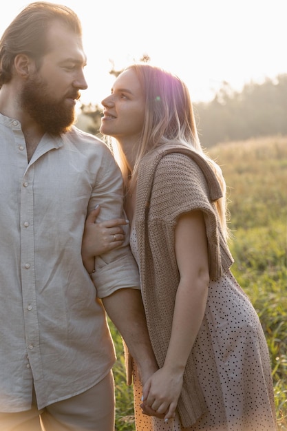 A young married couple walks in beige outfits in the park and hugs in the beautiful sunset light of the sun