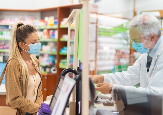 Young masked woman checking out in a pharmacy, coronavirus concept