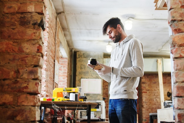 A young master paints a wooden piece in a handmade workshop