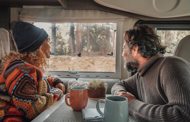 Young mature couple enjoy time inside camper van in van life lifestyle vacation Travel people concept lifestyle Admiring freedom nature park outdoors view outside the window Rv vehicle renting