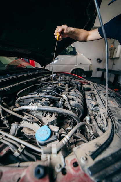 Young mechanic checking engine oil level in car