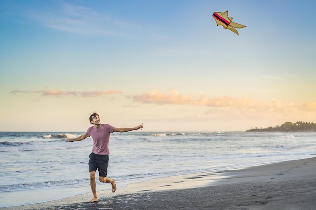 Young men flying a kite at sunset on the beach