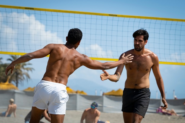 young men playing beach volleyball on the beach on a sunny day