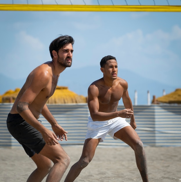 young men playing beach volleyball on the beach on a sunny day