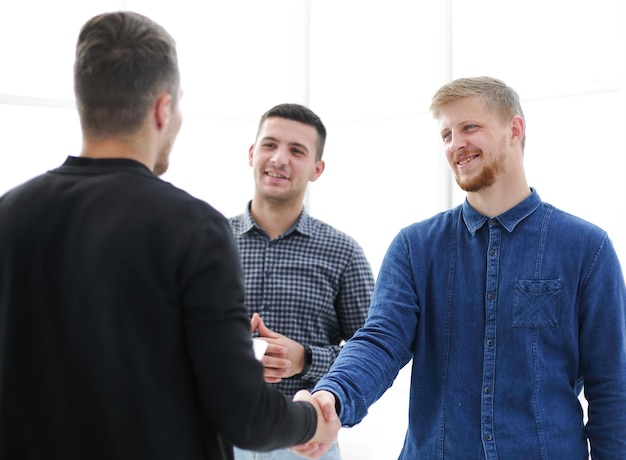 Photo young men shaking hands in a creative office