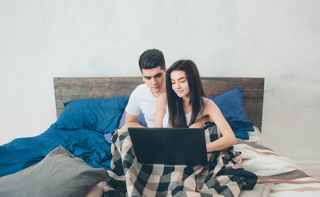 Young men and women are working on the computer or looking for information on the Interneton the bed