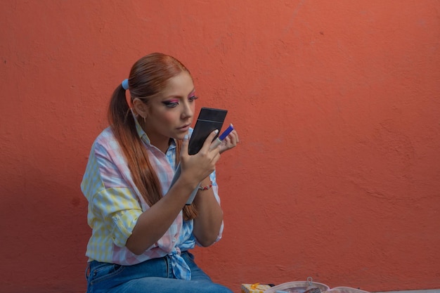 A young Mexican dancer adjusts her dress and prepares her makeup for a traditional dance