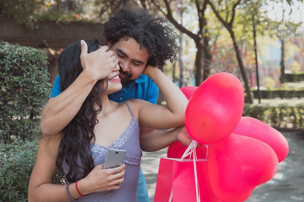 Young Mexican man surprises his girlfriend in the park by covering her eyes on Valentine's Day