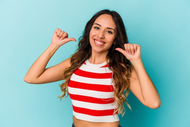 Young mexican woman isolated on blue wall feels proud and self confident, example to follow.