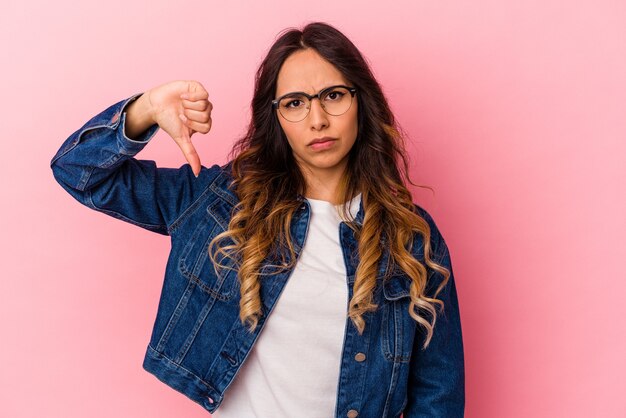 Young mexican woman isolated on pink background showing thumb down, disappointment concept.