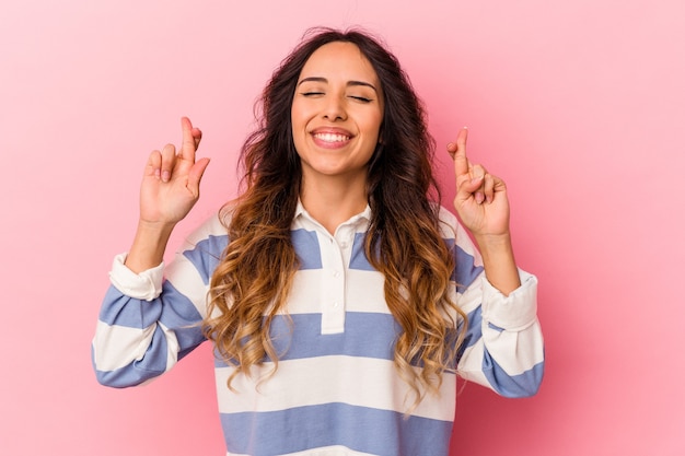 Photo young mexican woman isolated on pink wall crossing fingers for having luck