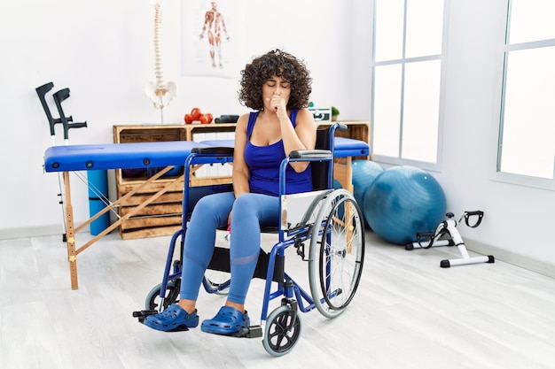 Young middle eastern woman sitting on wheelchair at physiotherapy clinic feeling unwell and coughing as symptom for cold or bronchitis health care concept