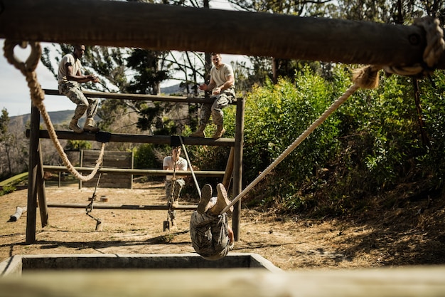 Young military soldiers practicing rope climbing during obstacle course